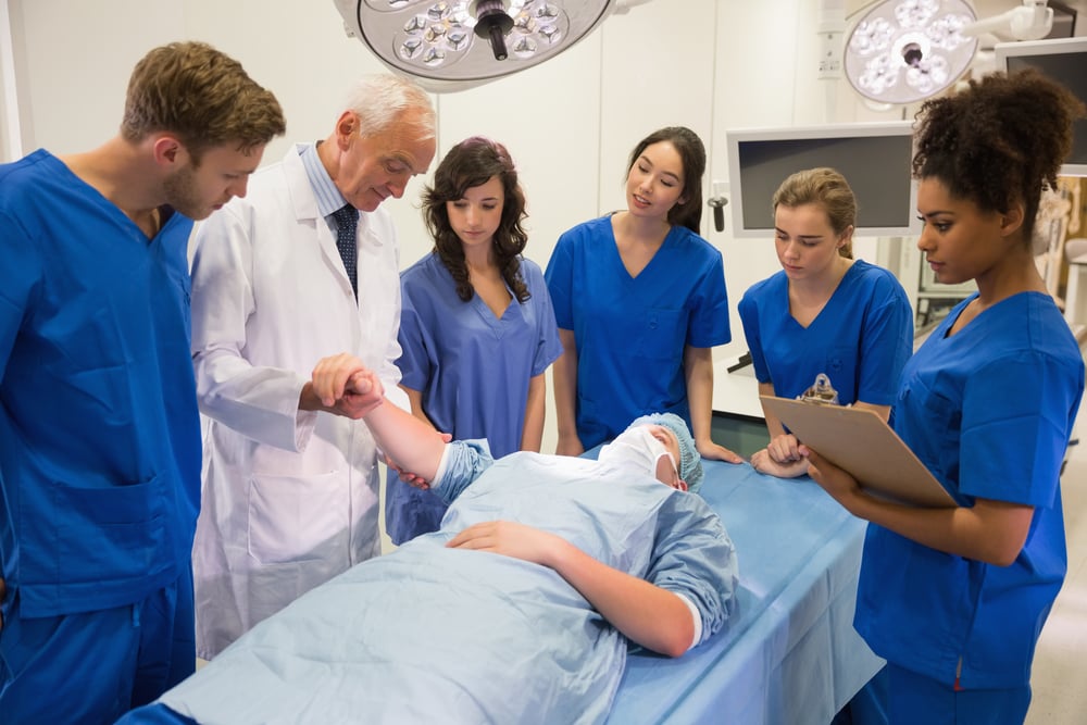 Medical students and professor checking pulse of student at the university